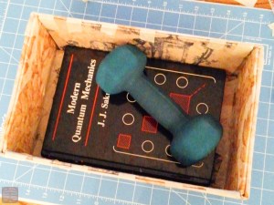 箱本体の外側と内側をまず作成。布に防水加工のようなものがされているのでしょうか、接着力が非常に弱く、錘を置いて待ちました。もう廃れてしまった量子物理学の本も大活躍です。